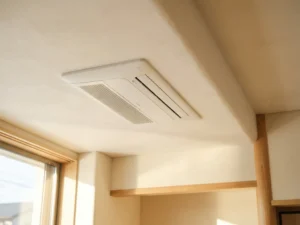 Witte cassette airconditioner gemonteerd tegen plafond met geometrische ventilatieroosters in natuurlijk daglicht