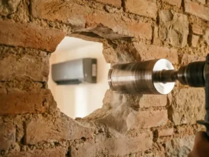 Diamond drill drilling a precise hole in a historic brick wall, with modern air conditioning visible in the background.